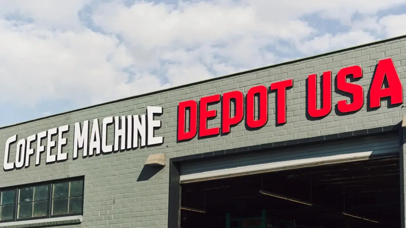 Exterior of Coffee Machine Depot USA warehouse with large red and white signage above an open garage door.